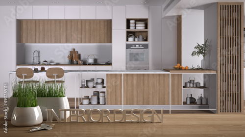 Wooden table, desk or shelf with potted grass plant, house keys and 3D letters making the words interior design, over kitchen with island project concept copy space background