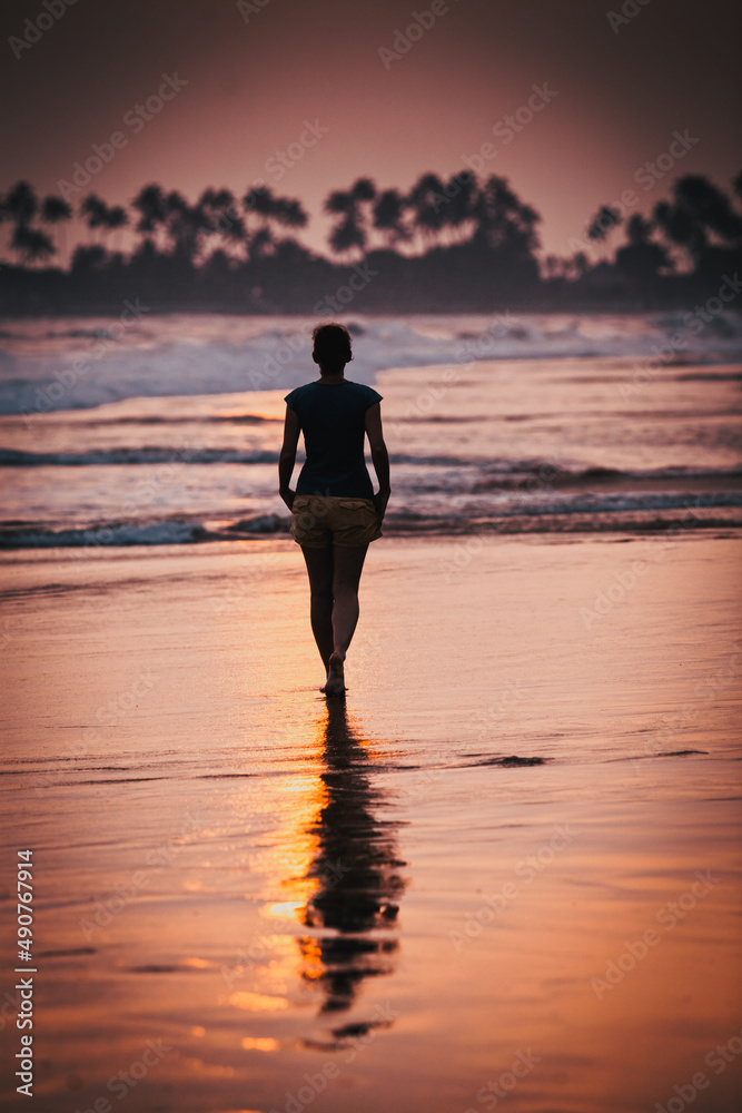 Fototapeta premium woman silhouette walking on sunset beach