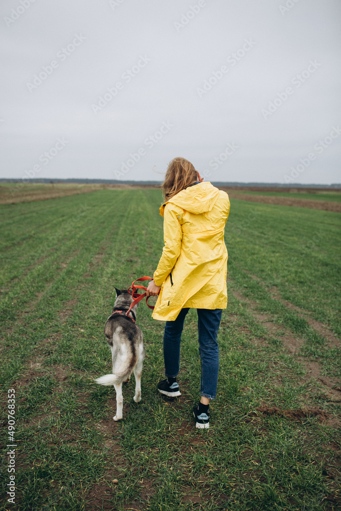 beautiful girl in a yellow raincoat on a green field. portrait of a woman in a yellow cloak with a husky dog. Love your dog and protect it from war. beautiful girl in a yellow raincoat on a green field. portrait of a woman in a yellow cloak with a husky dog. Love your dog and protect it from war.