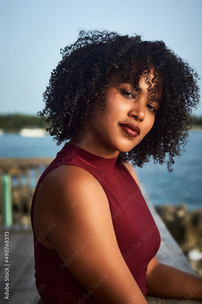 Latin girl with curly hair looking towards the beach on the pier Latin girl with curly hair looking towards the beach on the pier