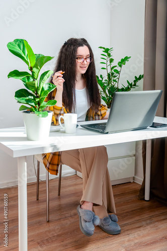 Beautiful woman in glasses talking on the video call on a workplace. Woman working at home,holds a conference, conducts a training or webinar © Svetlana Belozerova