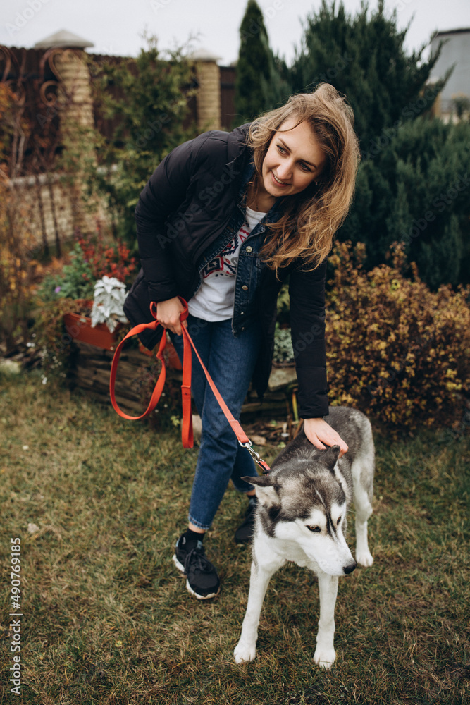 beautiful girl hugging her dog husky. Take care of animals during the war. Husky and beautiful woman in the yard beautiful girl hugging her dog husky. Take care of animals during the war. Husky and beautiful woman in the yard