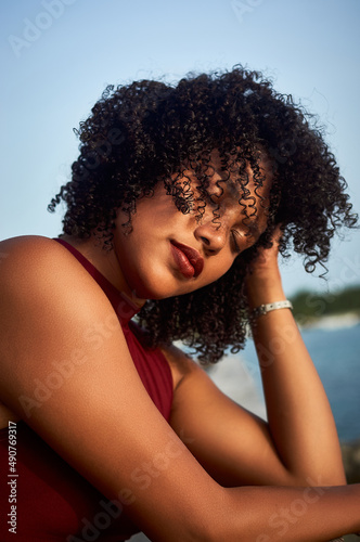 Latin girl with curly hair looking towards the beach on the pier