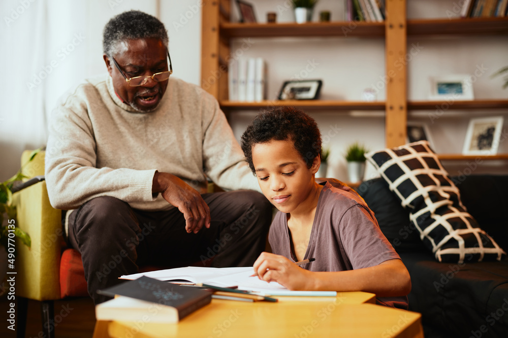 A grandfather looking at his grandchild's homework and checking on him at home. A grandfather looking at his grandchild's homework and checking on him at home.