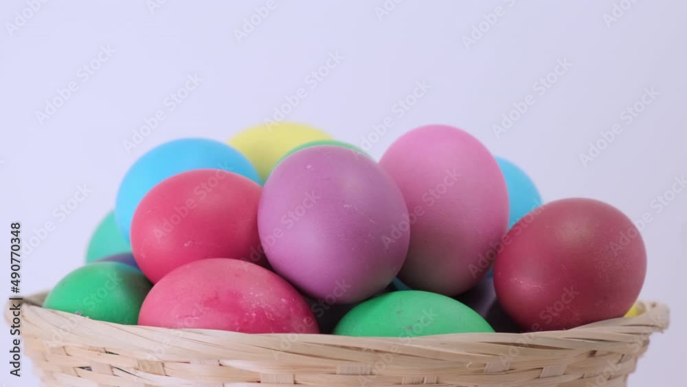 Colorful Easter chicken eggs rotating in basket. Egg are rolling on light background. Happy easter