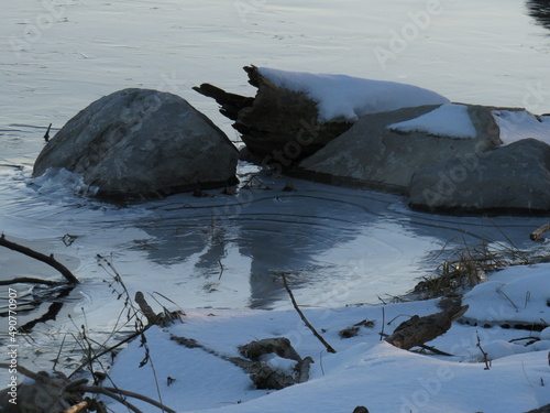 Close-up of rocks in the water, at the beginning of winter, with white snow and freezing water