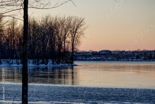 Tranquil scenery at the beginning of winter with the river partly frozen and bare trees