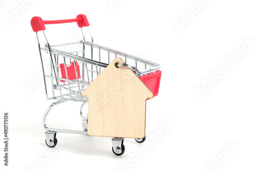 Shopping cart and keychain in the form house with keys white background.Purchase housing and real estate.
