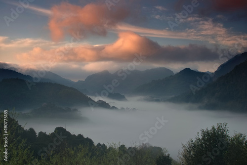 Colorful sky over sea of fog in a valley in a morning
