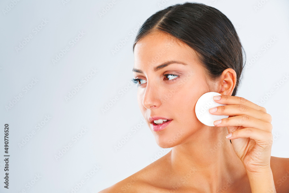 Keeping her pores clean. A beautiful young woman wiping her cheeks with a cotton swab. Keeping her pores clean. A beautiful young woman wiping her cheeks with a cotton swab.