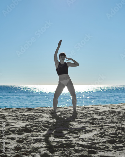 A selective color photo of a woman dancing in the beach