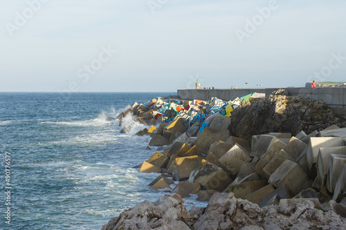 waves crashing against the decorated breakwater of Llanes photo
