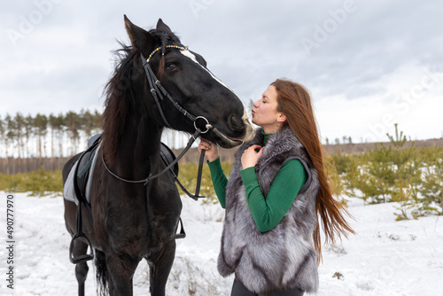 A woman and a black horse on a walk. Favorite pet. Horse riding in winter © Galina