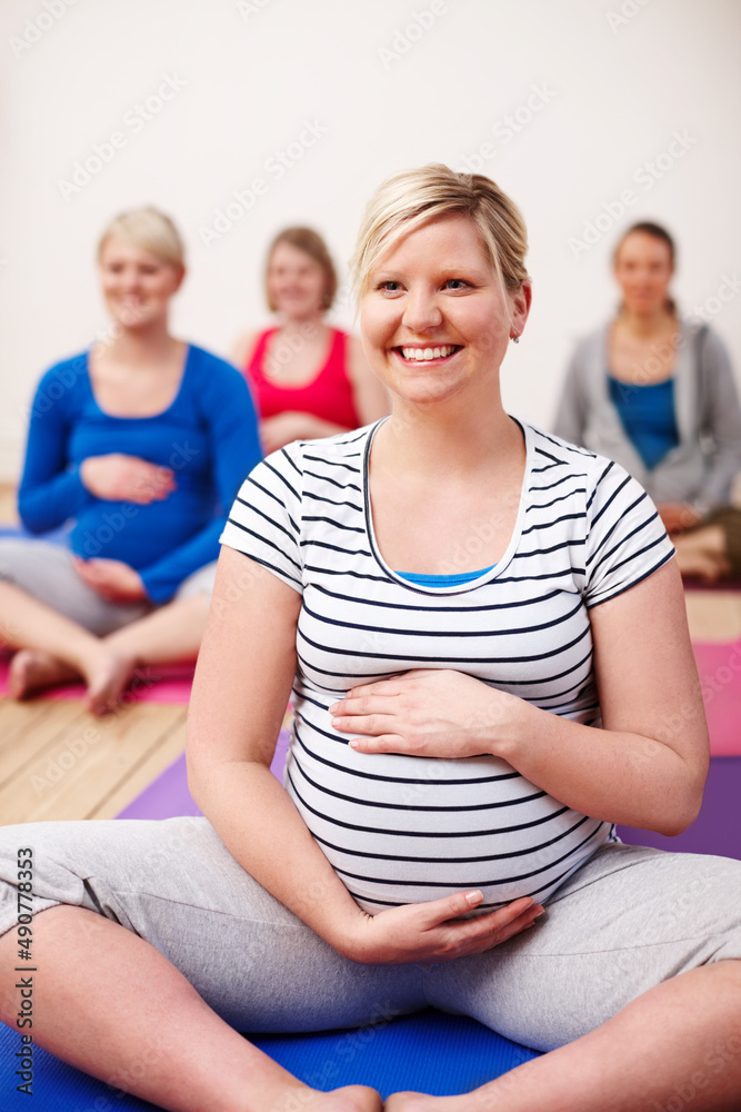 My focus is on a calm birth. A group of pregnant women sitting cross-legged in a yoga class and smiling happily. My focus is on a calm birth. A group of pregnant women sitting cross-legged in a yoga class and smiling happily.