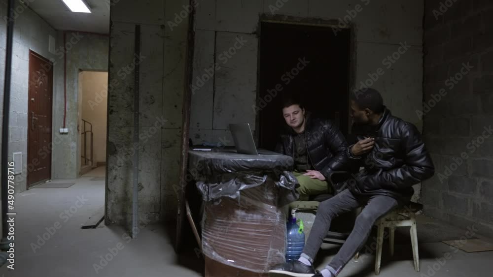 Caucasian guy and black guy are hiding in a basement during a war and having a talk Caucasian guy and black guy are hiding in a basement during a war and having a talk