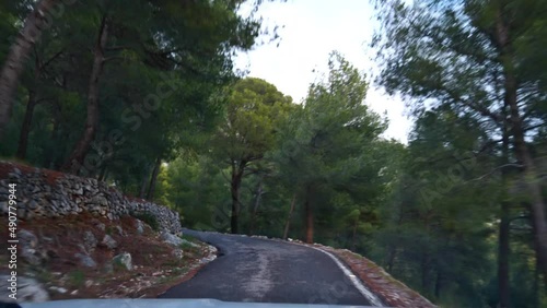 Front view of car driving on narrow curvy road to the peak of mountain Mont Faron near Toulon, France at the French Riviera with rocks and green trees passing by. photo