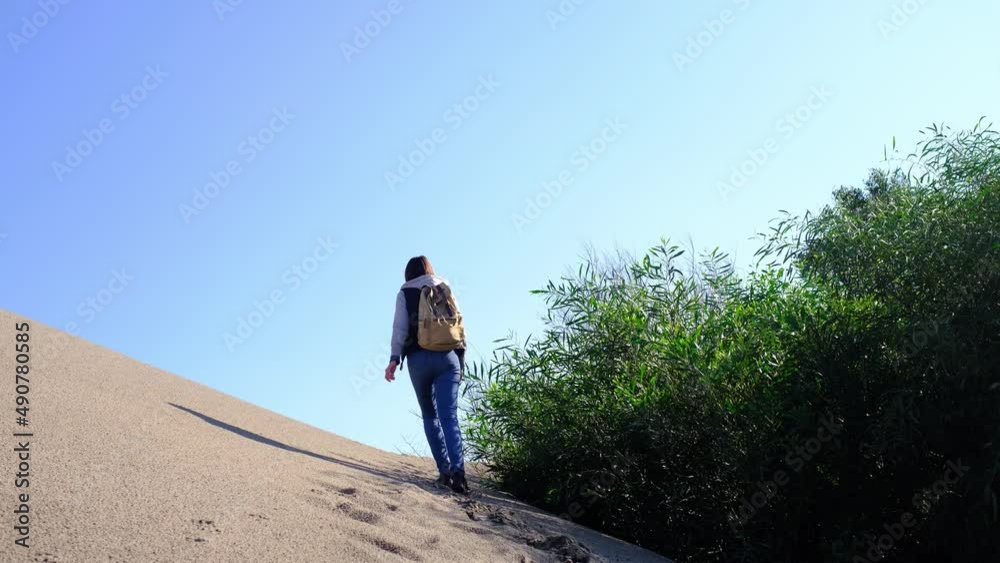 Backpacker female walking on Patara sand dunes beach enjoying windy Mediterranean Sea during Lycian Way trekking back or rear view. Famous Likya Yolu Turkish route. Active people vacation concept