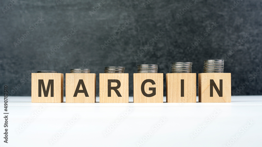 margin word, text written on wooden cubes on a black background with coins on cubes margin word, text written on wooden cubes on a black background with coins on cubes
