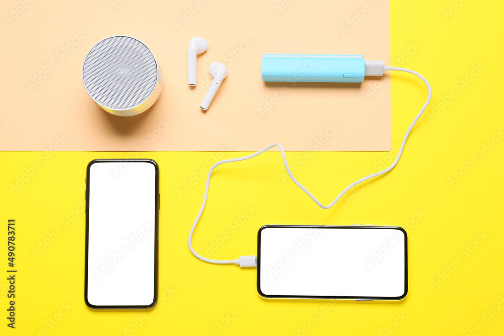Blue power bank with modern gadgets on color background Blue power bank with modern gadgets on color background