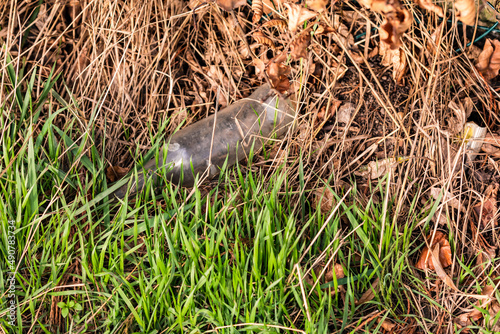 Eine weiße Glasflasche hinter Grashalmen wurde in Europa einfach in der Umwelt entsorgt