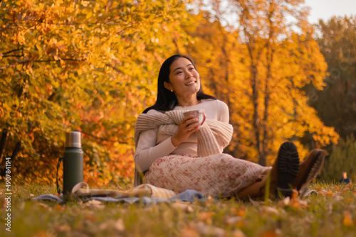 Optimistic businesswoman on a weekend relaxing in a natural setting, taking a picnic holding a cup of tea enjoying life on a warm autumn day in October.