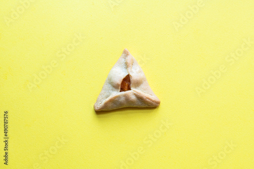 One hamantaschen cookie on yellow background. Top view.