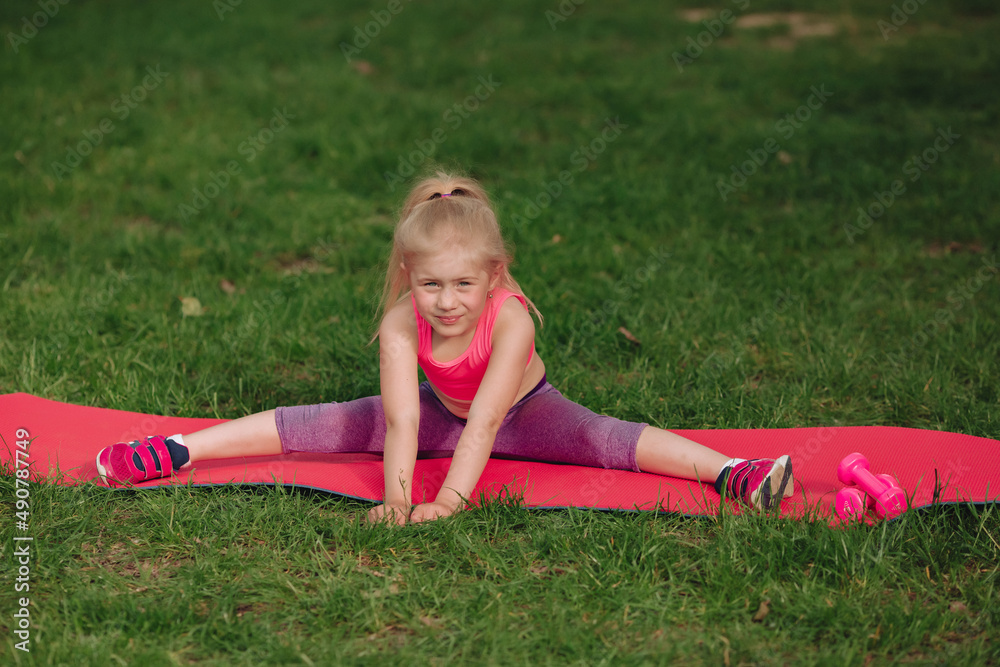 7 year old girl trains twine on fitness mat in field. 7 year old girl trains twine on fitness mat in field.