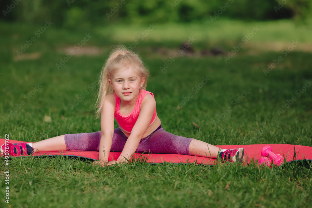 7 year old girl trains twine on fitness mat in field. 7 year old girl trains twine on fitness mat in field.