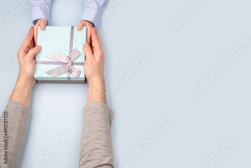 a father receives a gift box with a bow from the hands of his child in close-up