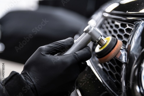 Car detailing technician polishing chrome shine decor on car with eletric polisher