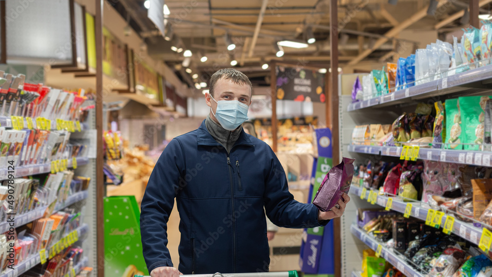 A man in a protective face mask chooses products in the store. Groceries. Food and drinks