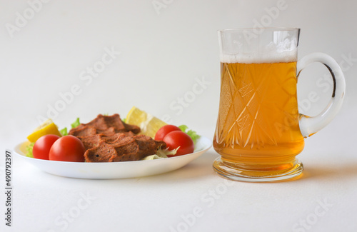 White background. Beer in a glass glass and cheesecake on a plate.