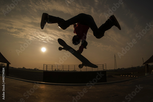 Skater doing a kick flip trick on a vert ramp at sunset