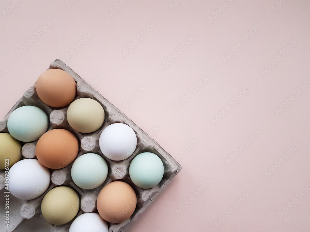 farm eggs are natural colored in an egg tray on a pink background. one is broken farm eggs are natural colored in an egg tray on a pink background. one is broken