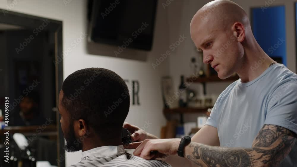 White hair stylist doing hairstyle to handsome young african american man White hair stylist doing hairstyle to handsome young african american man