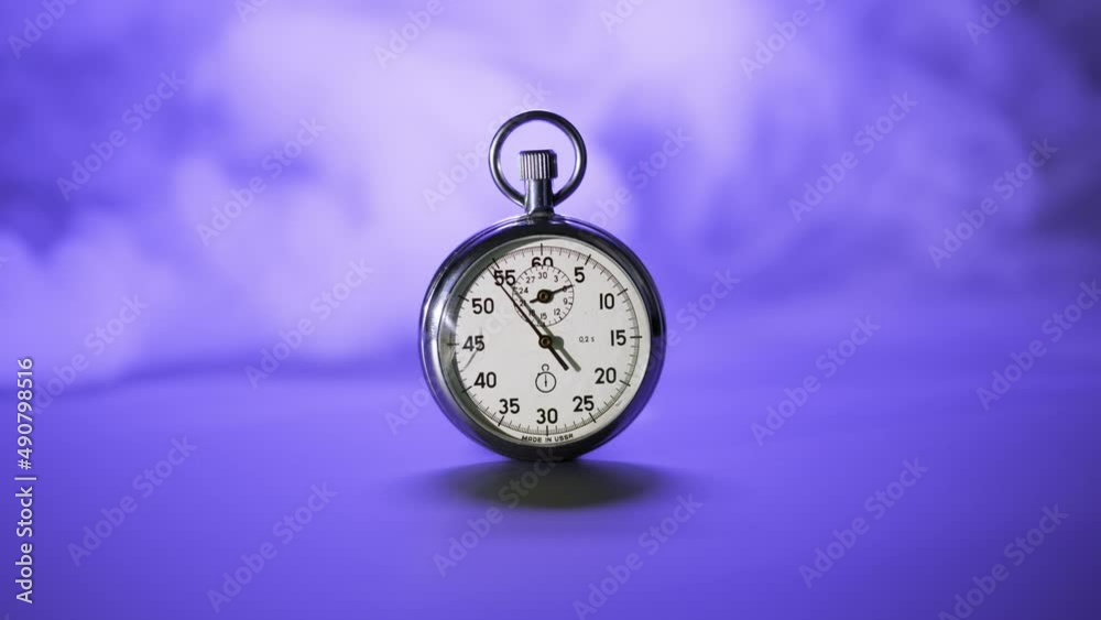 Chromed retro stopwatch counts down time to deadline of business processes. vintage stopwatch on very peri color background with smoke, time is running out. End of countdown or start new minute Chromed retro stopwatch counts down time to deadline of business processes. vintage stopwatch on very peri color background with smoke, time is running out. End of countdown or start new minute