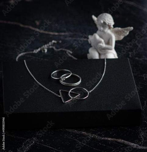 Silver necklace and rings on the dark marble