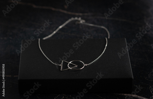 Silver necklace and rings on the dark marble