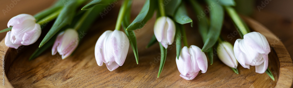 delicate tulips of pale color lie on a beautiful wooden tray delicate tulips of pale color lie on a beautiful wooden tray