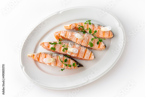 Grilled salmon fillet with sauce on a white plate. Banquet festive dishes. Gourmet restaurant menu. White background.