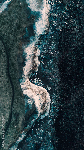 Top view of the collision of sea waves with foam to the rock photo