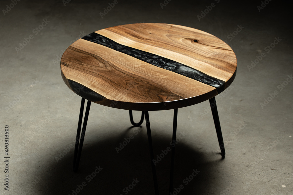 Expensive vintage furniture. The table is covered with epoxy resin and  varnished. Luxury quality wood processing. Reflections of light in polished  varnish.A black epoxy river in a round tree slab. Stock Photo