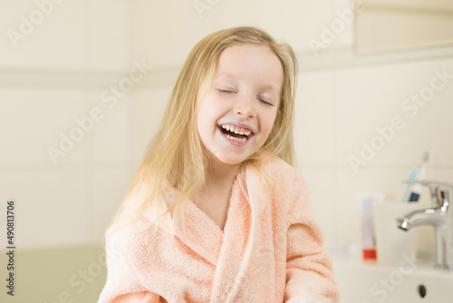 Happy smiling little girl brush teeth using ultrasonic electric toothbrush in bathroom at home. Oral hygiene, dental and gum health, healthy teeth. Daily life and routine.