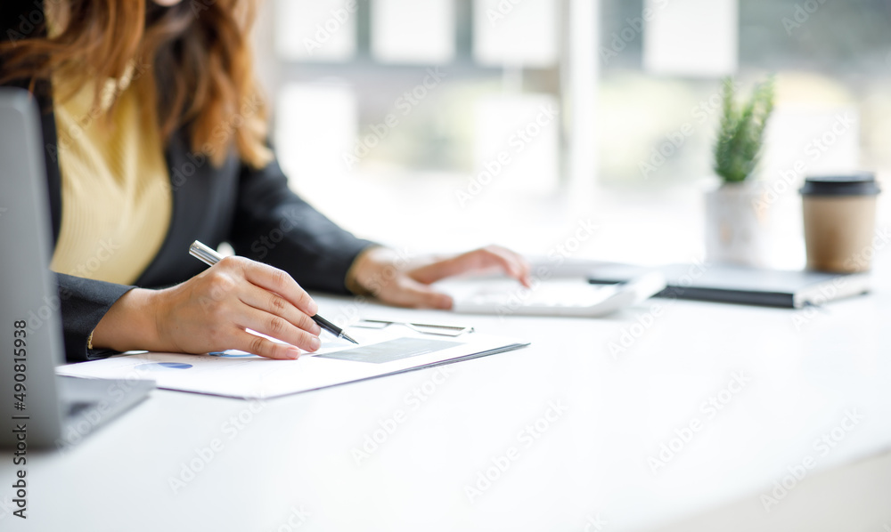 Close up of businesswoman working on desk office with using a calculator to calculate the numbers, finance accounting concept Close up of businesswoman working on desk office with using a calculator to calculate the numbers, finance accounting concept