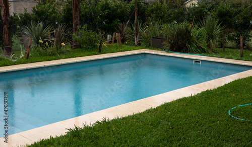 The house rectangular swimming pool and green grass in the backyard. © Gonzalo
