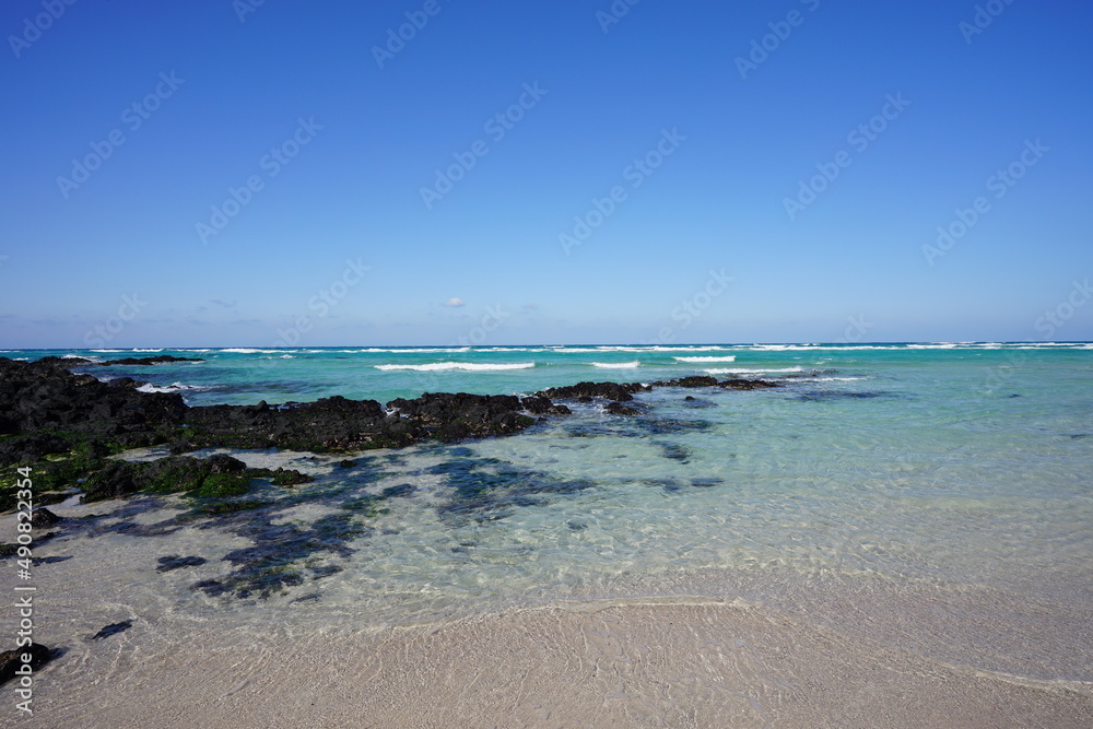 clear shoaling beach with rocks