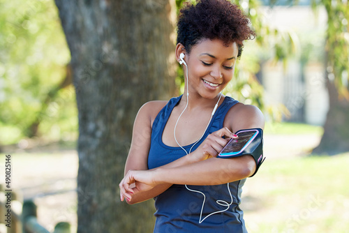 Setting the perfect playlist to get her started. Cropped shot of a sporty young woman checking her playlist before a run.