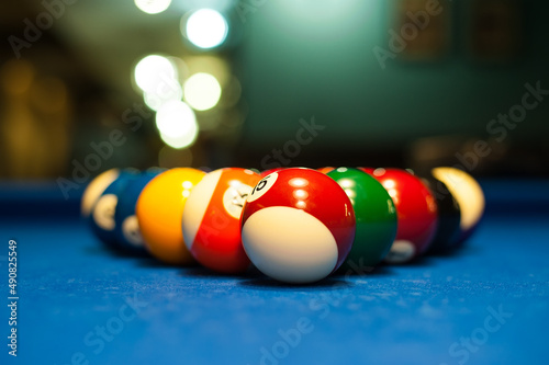 multicolored billiard balls lie in a triangle on a table with a blurred background