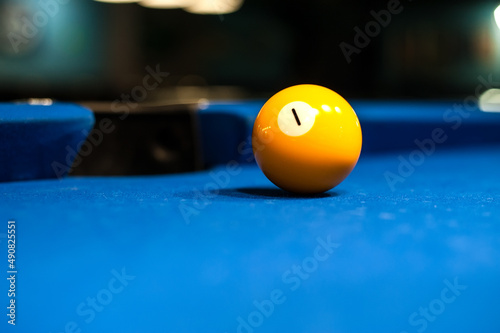 yellow billiard ball floor number one is lying on the table with a blurred background