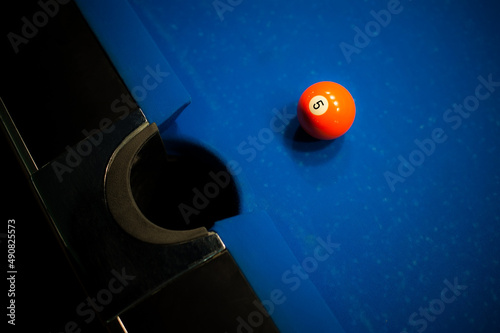 orange billiard ball number one is on the blue table at the pocket